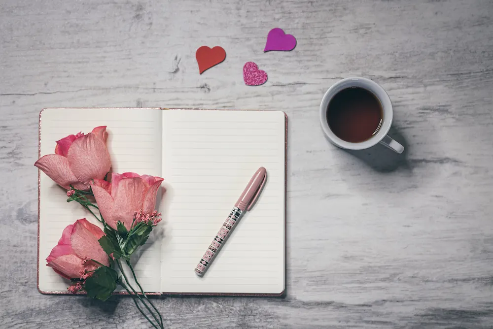 An open manifestation journal with roses and coffee, ready for the 3-6-9 scripting method.