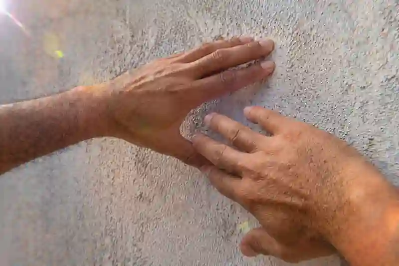 Two hands with visible skin grit and veins near a cracked wall, representing the final blueprint for successful love manifestation.