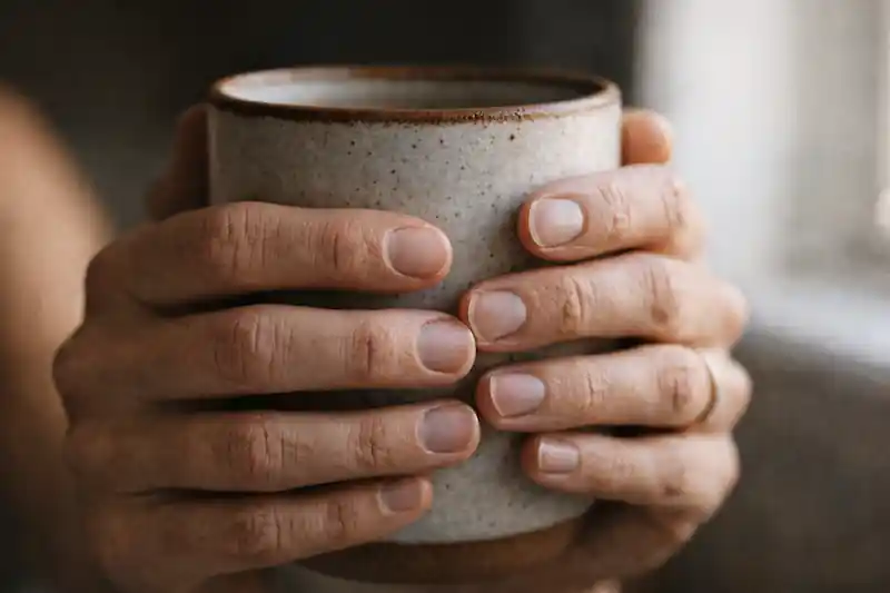 Candid 10K photography of hands with dry cuticles on a wooden table, representing the lack of emotional safety in love manifestation.