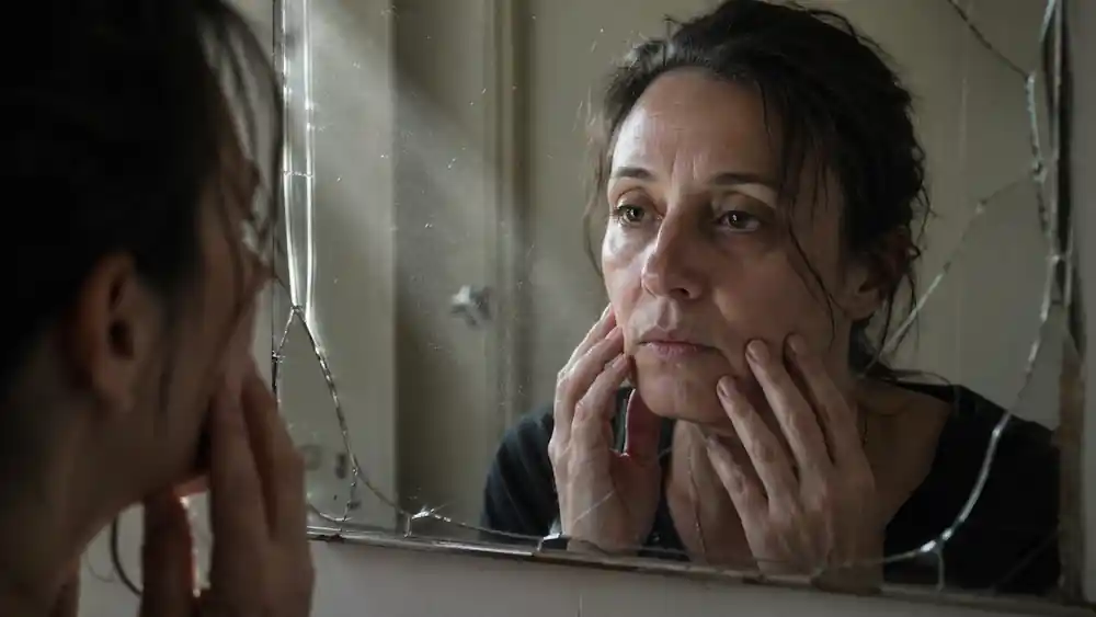 Candid shot of a woman with messy hair, looking into a mirror, focusing on her Reticular Activating System (RAS) and 777 alignment method.