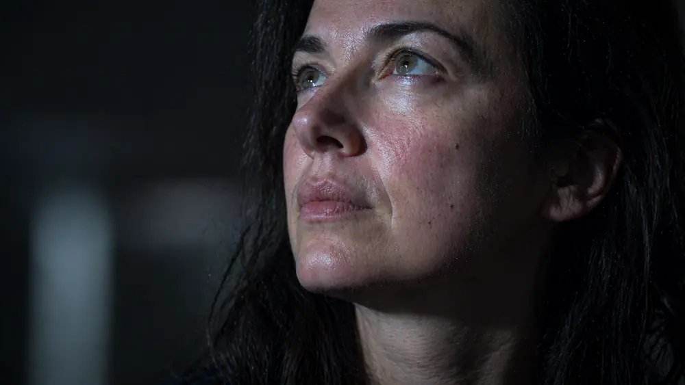 Close-up of a woman looking at the Scorpio Full Moon with an expression of financial survival loop anxiety, raw skin texture.