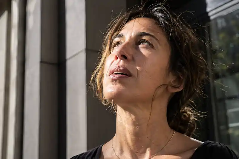 Candid shot of a woman looking upward, visible neck tendons and tech-neck lines, sealing the frequency shift of the Full Moon in Scorpio May 1st 2026.