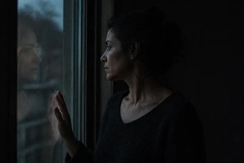 A woman looking out a window at night, symbolizing lunar synchronization and the Moon Phase Soulmate Test
