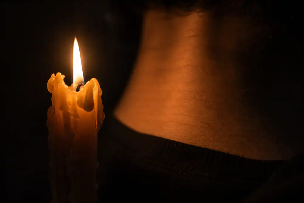 A dramatic, raw photograph of a flickering candle flame in a dark, textured room, symbolizing the closing window of a 55 portal spiritual reset.