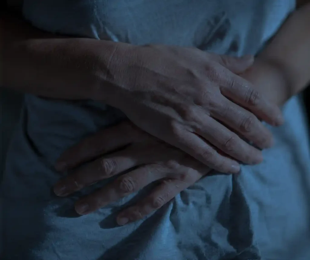 Close-up of a woman's hand on her stomach reflecting Blue Moon light, showing red moon cycle hormonal shift.